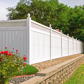 Picture of white vinyl fence and brick landscaping with pink rose bushes
